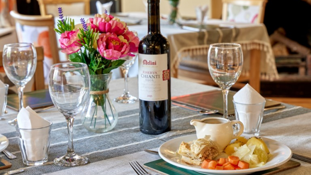 Bridge House dining table, bottle of wine, a meal and flowers 